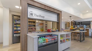 A modern retail area with a refrigerated display, shelves stocked with snacks, and a counter with beverages. - Hilton Garden Inn Albany/SUNY Area (Albany)