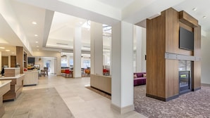 A spacious hotel lobby with a reception desk, seating areas, and a fireplace. - Hilton Garden Inn Albany/SUNY Area (Albany)
