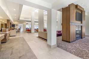A spacious hotel lobby with a reception desk, seating areas, and a fireplace. - Hilton Garden Inn Albany/SUNY Area (Albany)