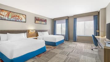 Une chambre d’hôtel avec deux lits, un bureau, une télévision et des œuvres d’art accrochées aux murs.