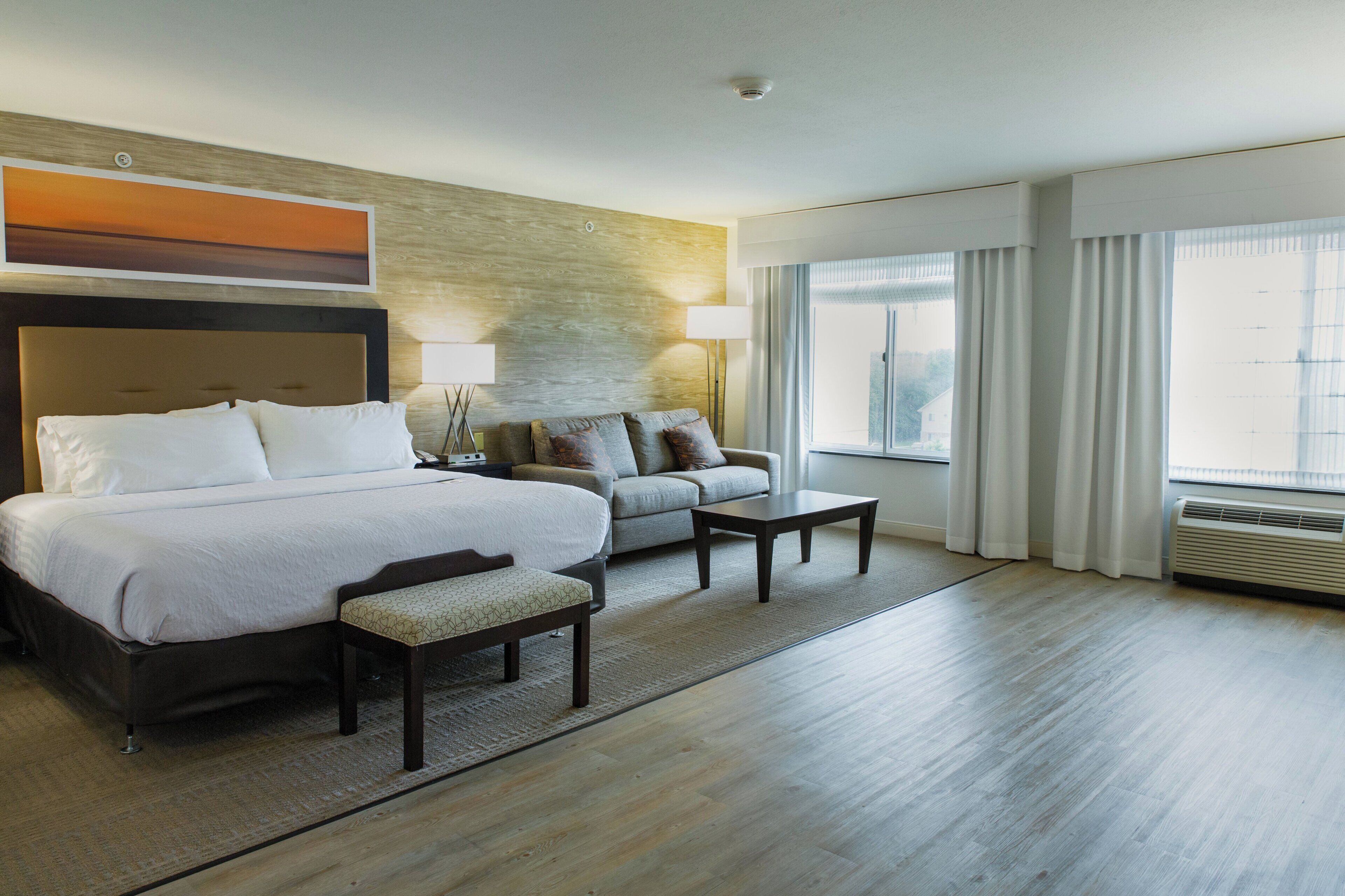A hotel room with a bed, a sofa, a coffee table, and a desk.