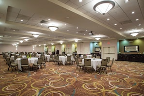 A large conference room with multiple tables and chairs, a carpeted floor, and ceiling lights.