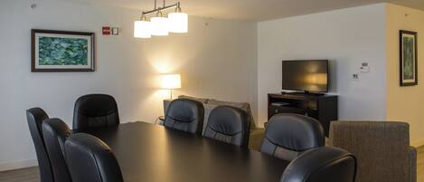 A modern living room with a dining table, chairs, a sofa, a television, and artwork on the walls.