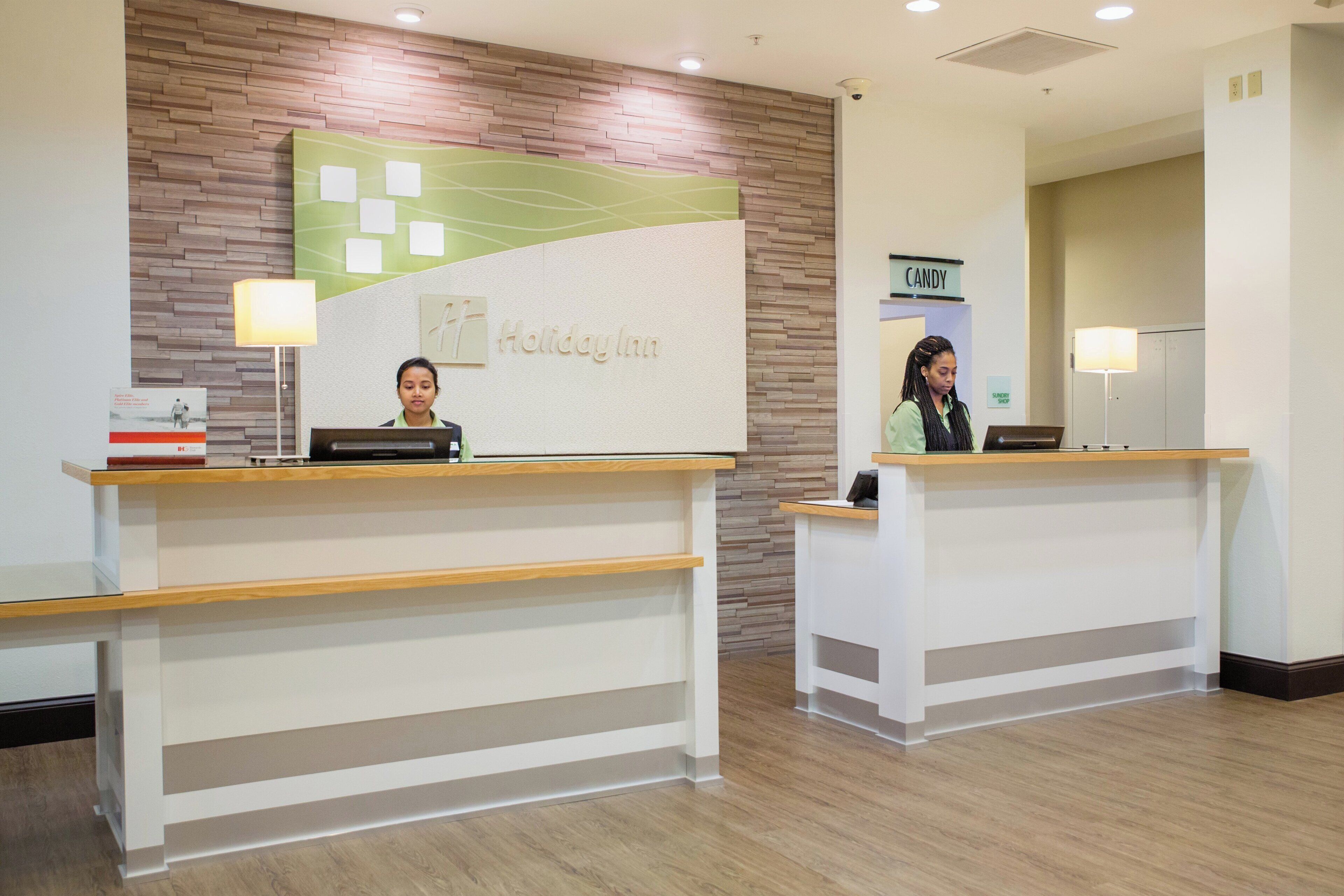 Un comptoir d’accueil avec une enseigne Holiday Inn, une enseigne pour une confiserie et une enseigne pour une boutique de produits divers.