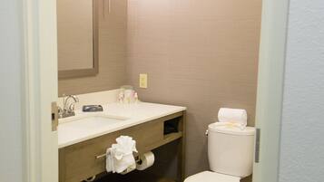 A bathroom with a wooden vanity, a sink, a mirror, a toilet, and a towel rack.