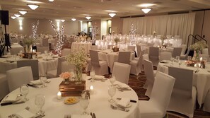 A banquet hall with round tables, white tablecloths, and chairs. - Holiday Inn Bloomington-Airport by IHG (Bloomington)