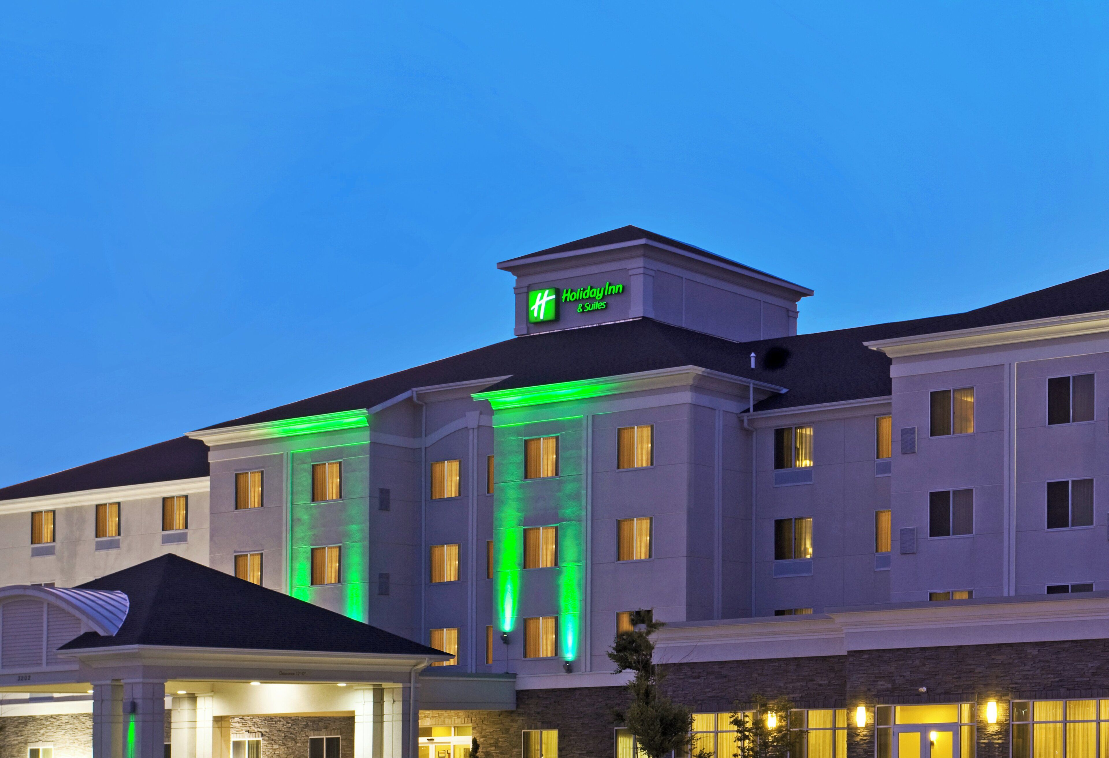 A Holiday Inn hotel with a modern facade, multiple windows, and a prominent green sign on the roof.
