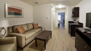 A modern living room with a sofa, coffee table, and a painting on the wall. - Holiday Inn Bloomington-Airport by IHG (Bloomington)