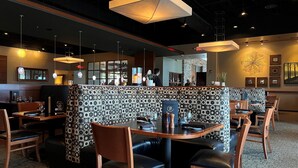 A restaurant with booths, tables, and a patterned wall. - Holiday Inn Bloomington-Airport by IHG (Bloomington)