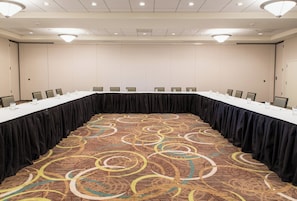 A conference room with a long table, chairs, and a patterned carpet.