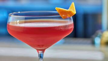 A cocktail in a martini glass with a lemon twist garnish.