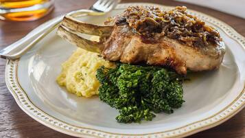 Een bord met een lamskotelet, gepureerde aardappelen en gestoomde broccoli.