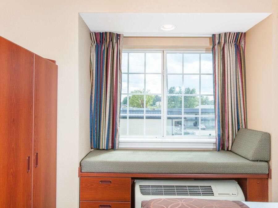 A room with a window, a bench, a wardrobe, and a heater.