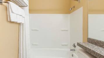 A bathroom with a white bathtub, a towel rack, and a granite countertop.