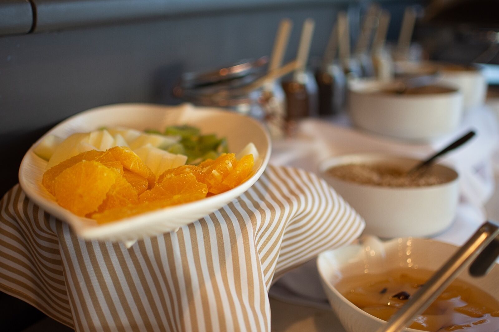 Une table avec un bol de tranches d’orange, un bol de soupe et un bol de sauce.