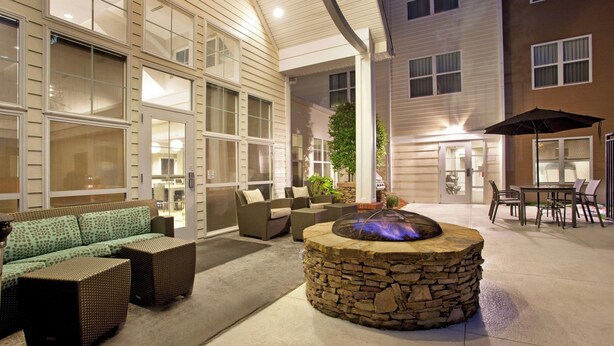 An outdoor patio with stone seating, a fire feature, and a dining area with umbrellas. - Residence Inn by Marriott Jackson Ridgeland (Ridgeland)