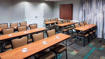 A conference room with multiple tables and chairs, a door, and a curtain.