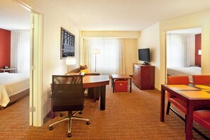 A hotel room with a bed, desk, office chair, television, and a small table with chairs.