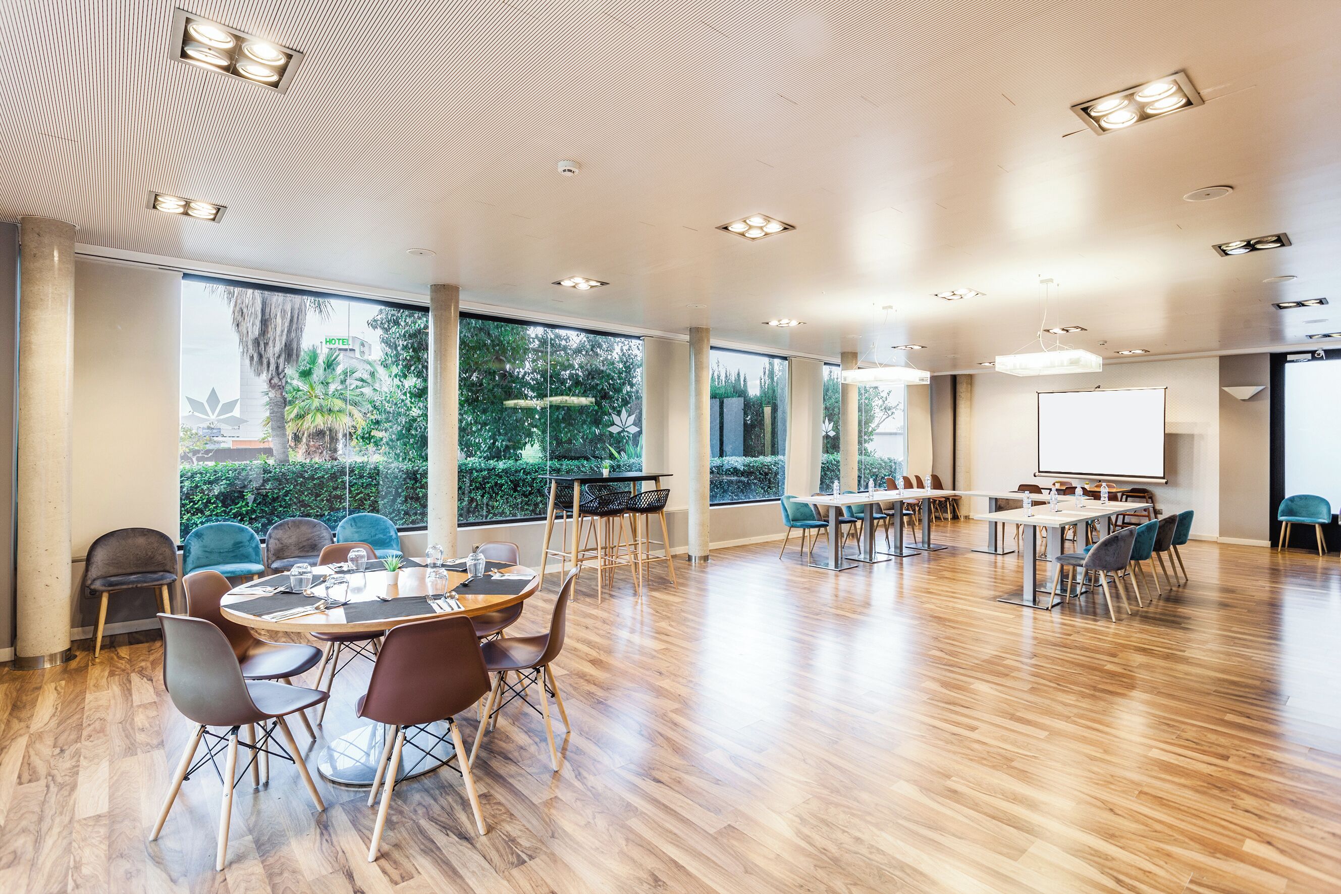 A spacious conference room with wooden floors, large windows, and modern lighting fixtures.