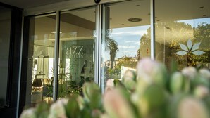 Entrada de hotel con puertas de vidrio, un interior visible con mobiliario y un letrero que dice "azz HOTELS".