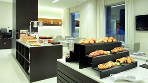Una mesa de buffet con diversas pastelerías y pan.