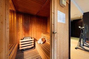 Eine Holzsauna mit Bänken und einer Sitzbank mit Handtüchern.