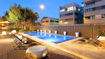 Relax by the pool surrounded by lounge chairs and sun loungers.