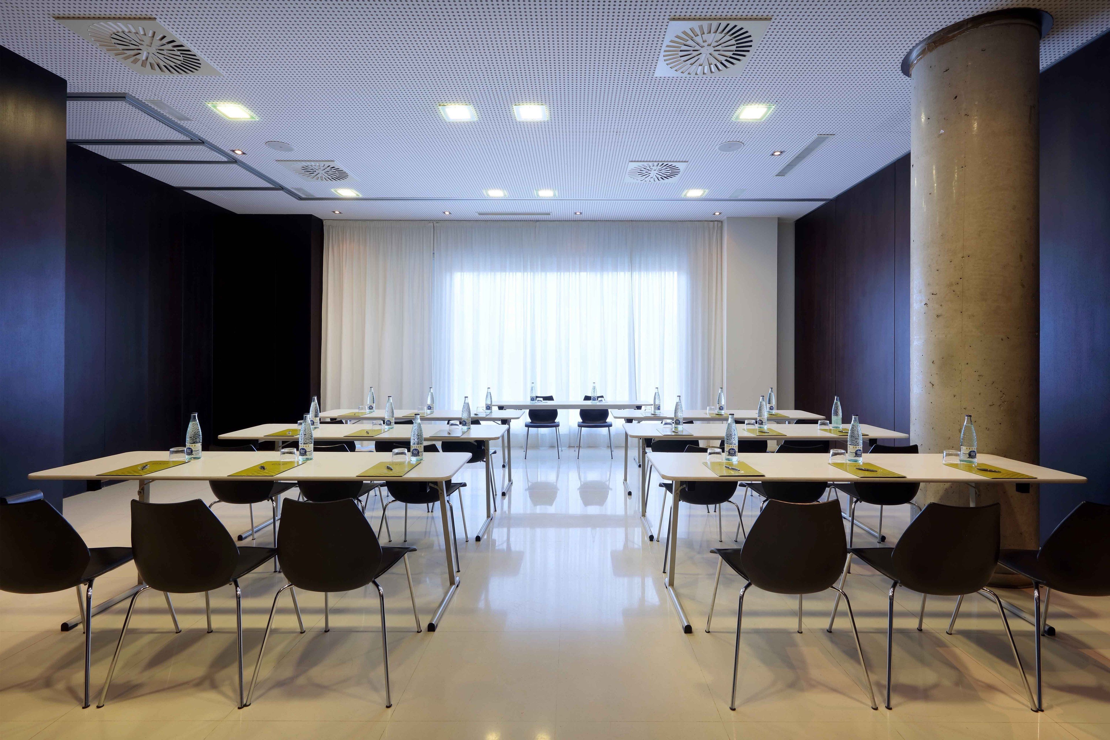 Una sala conferenze con tavoli, sedie e un'imponente colonna.
