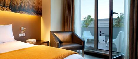 Une chambre d’hôtel avec un grand lit, une chaise, un bureau et un balcon avec vue.