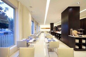 Eine moderne Hotelhalle mit einer langen Rezeption, einer Sitzecke und Blick ins Freie.