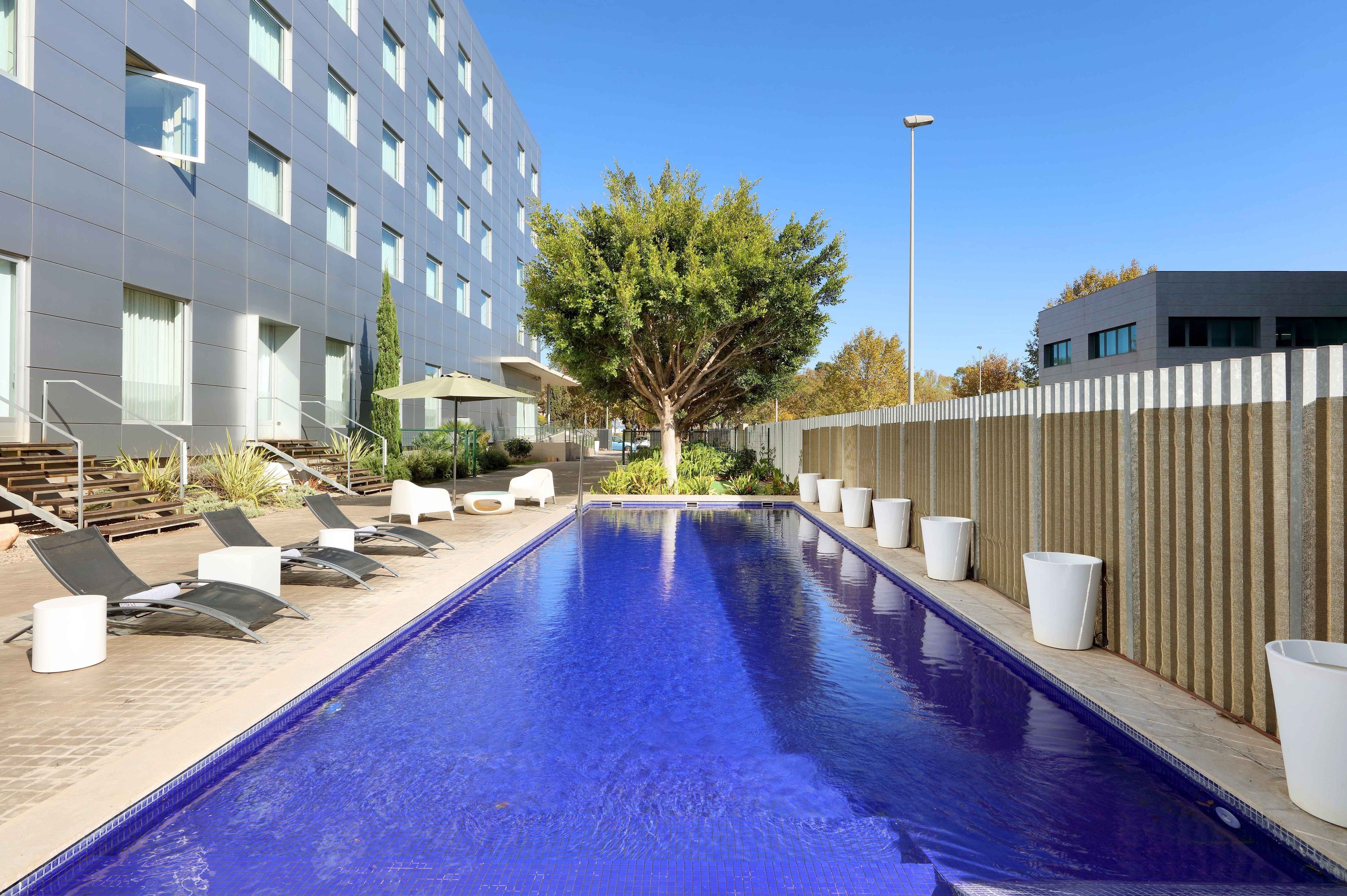 Una piscina con sillas de descanso y una valla de madera.