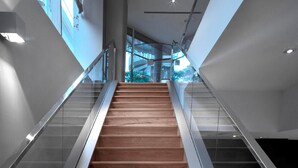 A modern staircase with wooden steps and glass railings, leading to an upper level.