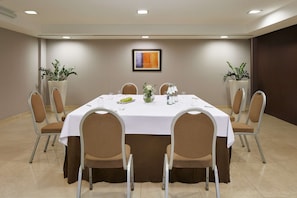 Conference room with a large table and eight chairs, surrounded by potted plants and artwork.