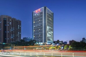 A high-rise building with a grid-like facade, surrounded by other buildings and a busy street with light trails. - Sichuan Hotel (Shenzhen)