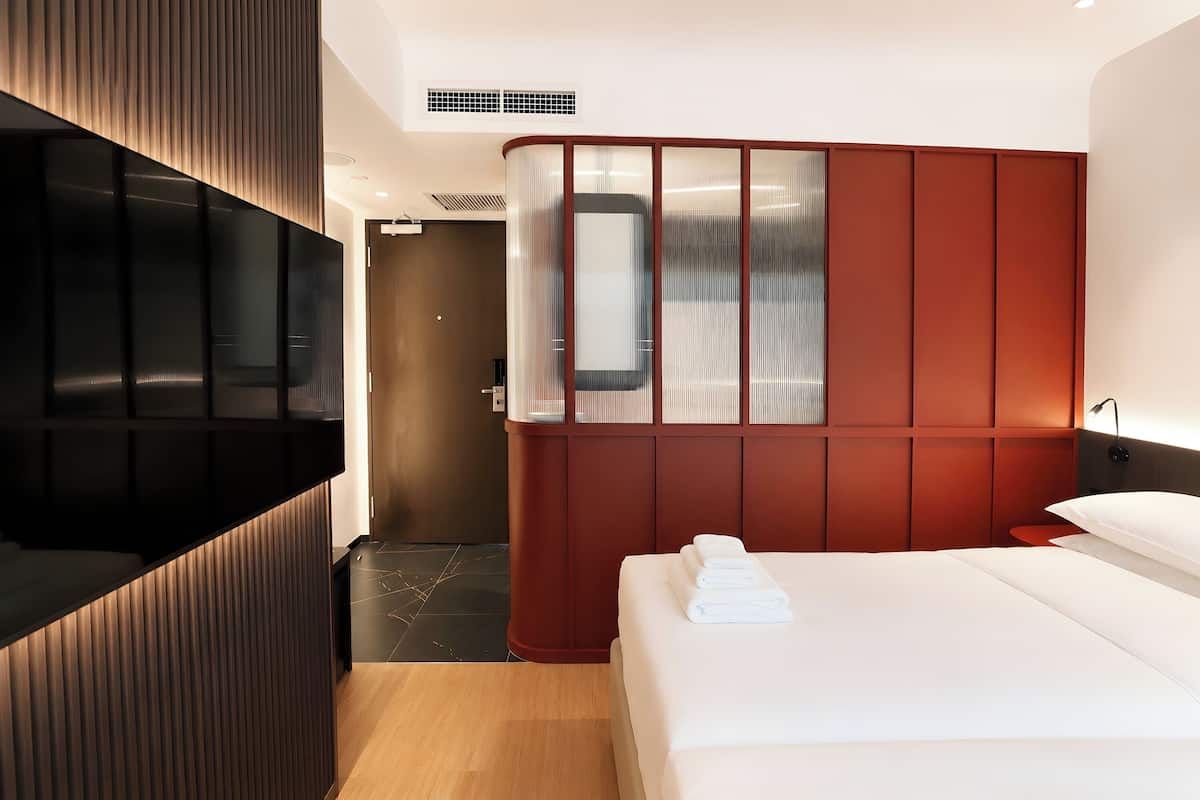 Habitación de hotel con cama, televisión, armario y espejo.