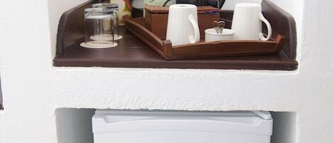 Una kitchenette con cafetera, tazas y una caja de jugo de manzana.