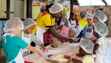 Un groupe d’enfants et d’adultes participait à un atelier de pâtisserie, tous coiffés de filets à cheveux et portant des tabliers.