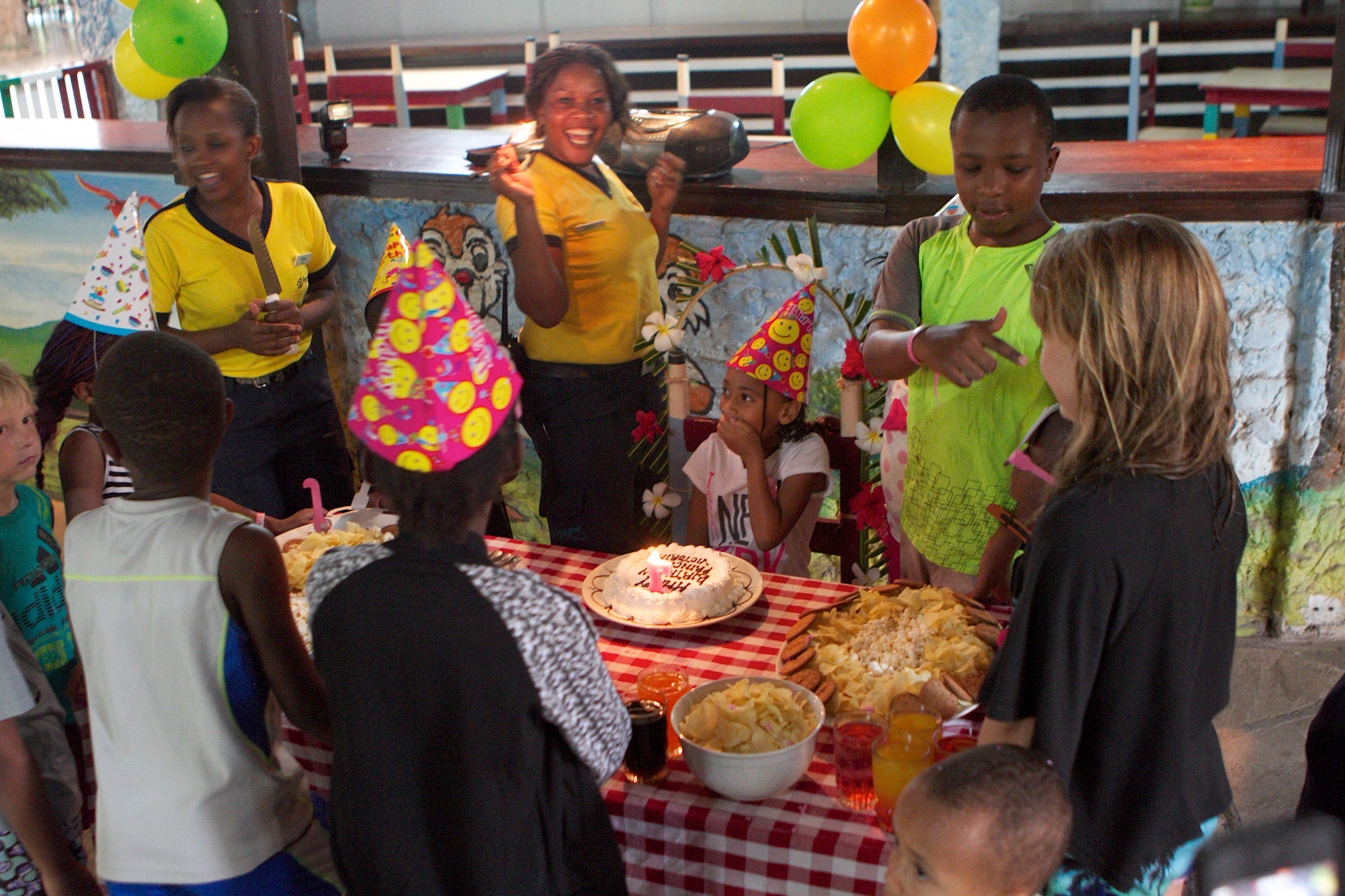 A group of people gathered around a table with a cake and food, suggesting a celebration or party.