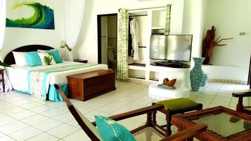Une chambre d’hôtel comprenant un lit, une télévision, un coin salon avec une table basse et une salle de bain visible à travers une porte ouverte.