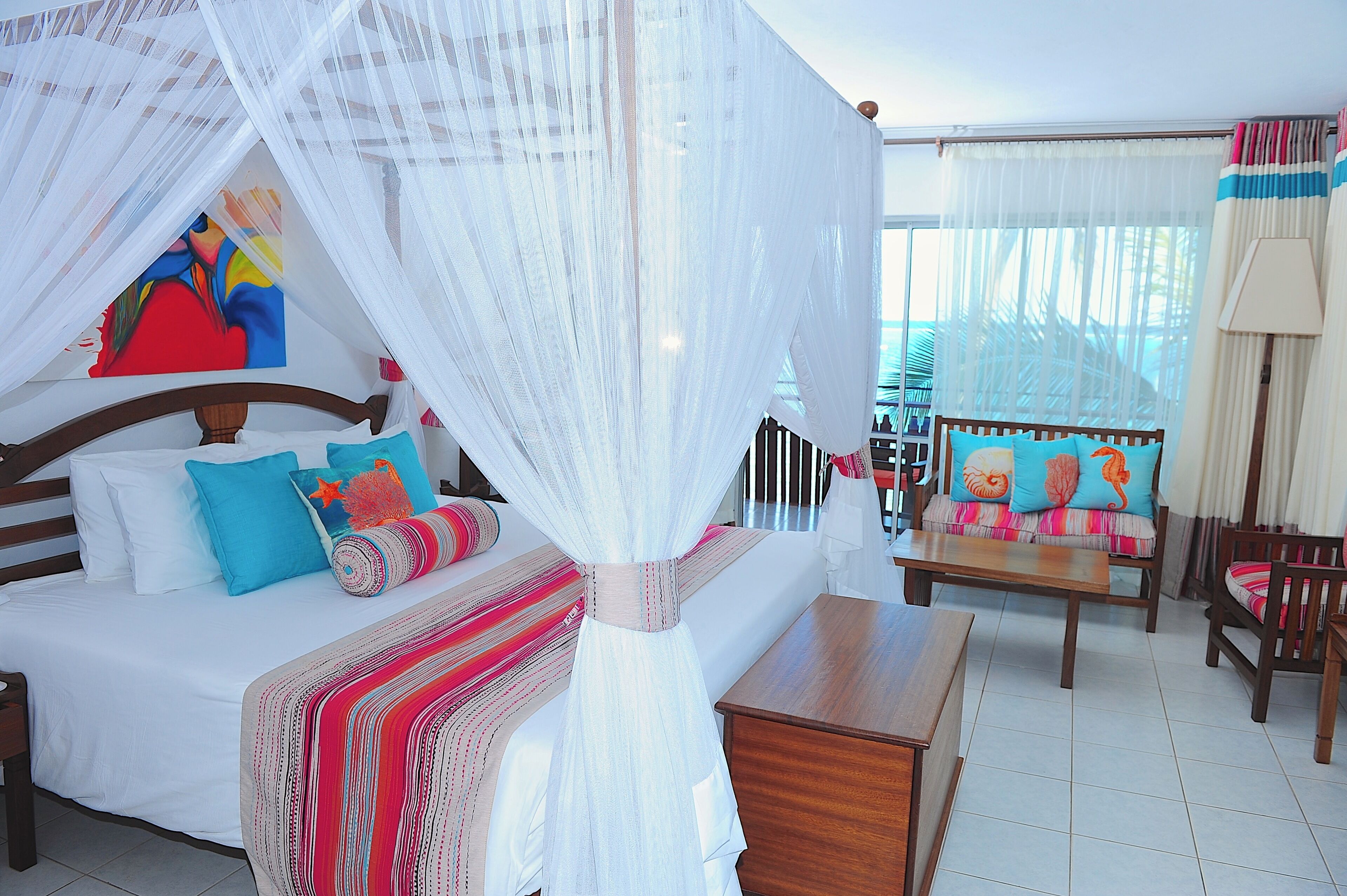 Un dormitorio con cama, mesita de noche, silla y ventana con cortinas.