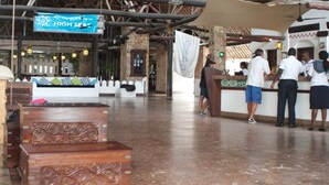 A spacious lobby with wooden benches, a reception desk, and a sign indicating a high-seas theme. - Voyager Beach Resort (Mombasa)