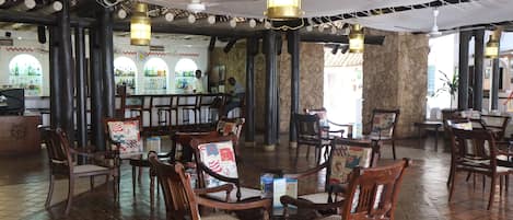 Un restaurant spacieux avec des chaises et des tables en bois, un coin bar et de grandes fenêtres surmontées d’arcs.