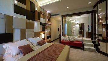 A modern hotel room with a large bed, a red sofa, and a mirror reflecting the bathroom.