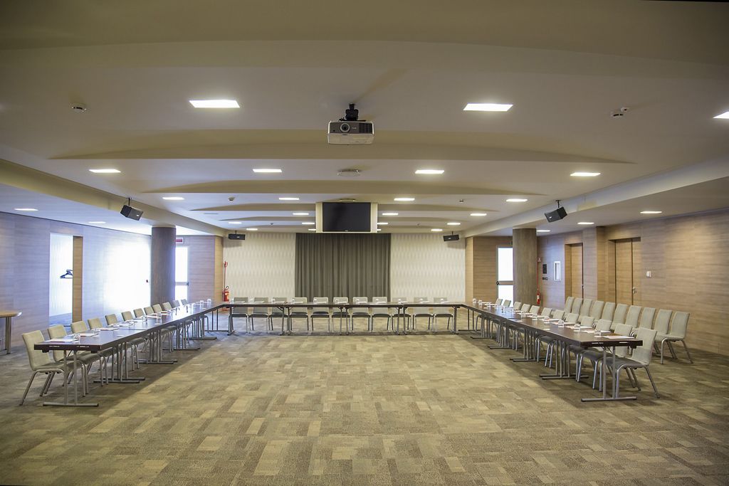 A conference room with a long table, chairs, a projector, and a screen.