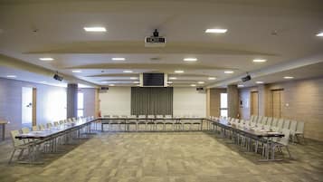 A conference room with a long table, chairs, a projector, and a screen.
