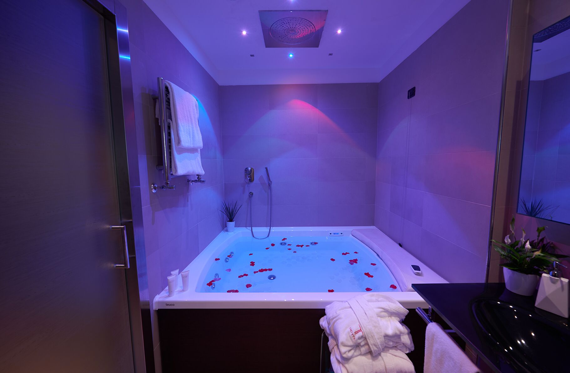 Ein modernes Badezimmer mit einer Badewanne, einer Dusche und einem Waschbecken. Handtücher und Toilettenartikel befinden sich auf der Ablagefläche.