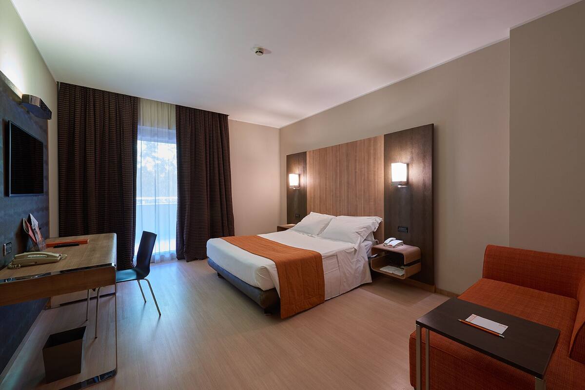 Een hotelkamer met een bed, bureau, stoel en een klein tafeltje.