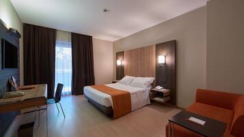 A hotel room with a bed, desk, chair, and a small table.