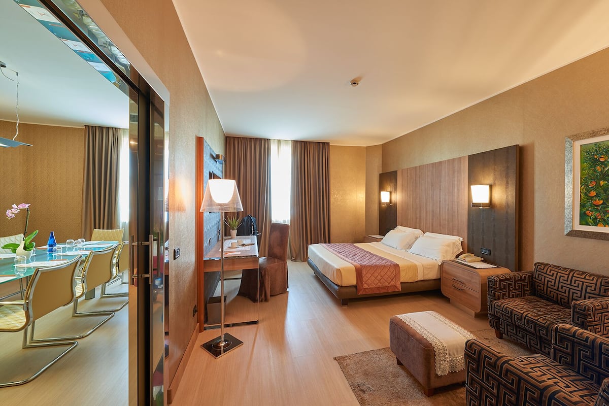 Een hotelkamer met een bed, een bureau met stoel, een bank en een schilderij aan de muur.