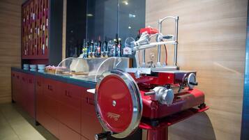 Zona de bar con un mostrador rojo, una vitrina de vidrio y una variedad de botellas al fondo.